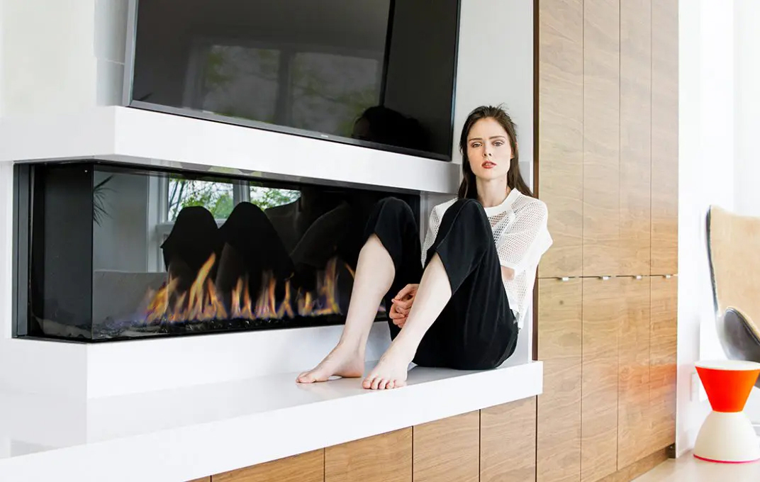 Coco Rocha in front of her new corner-style modern gas fireplace by Element4