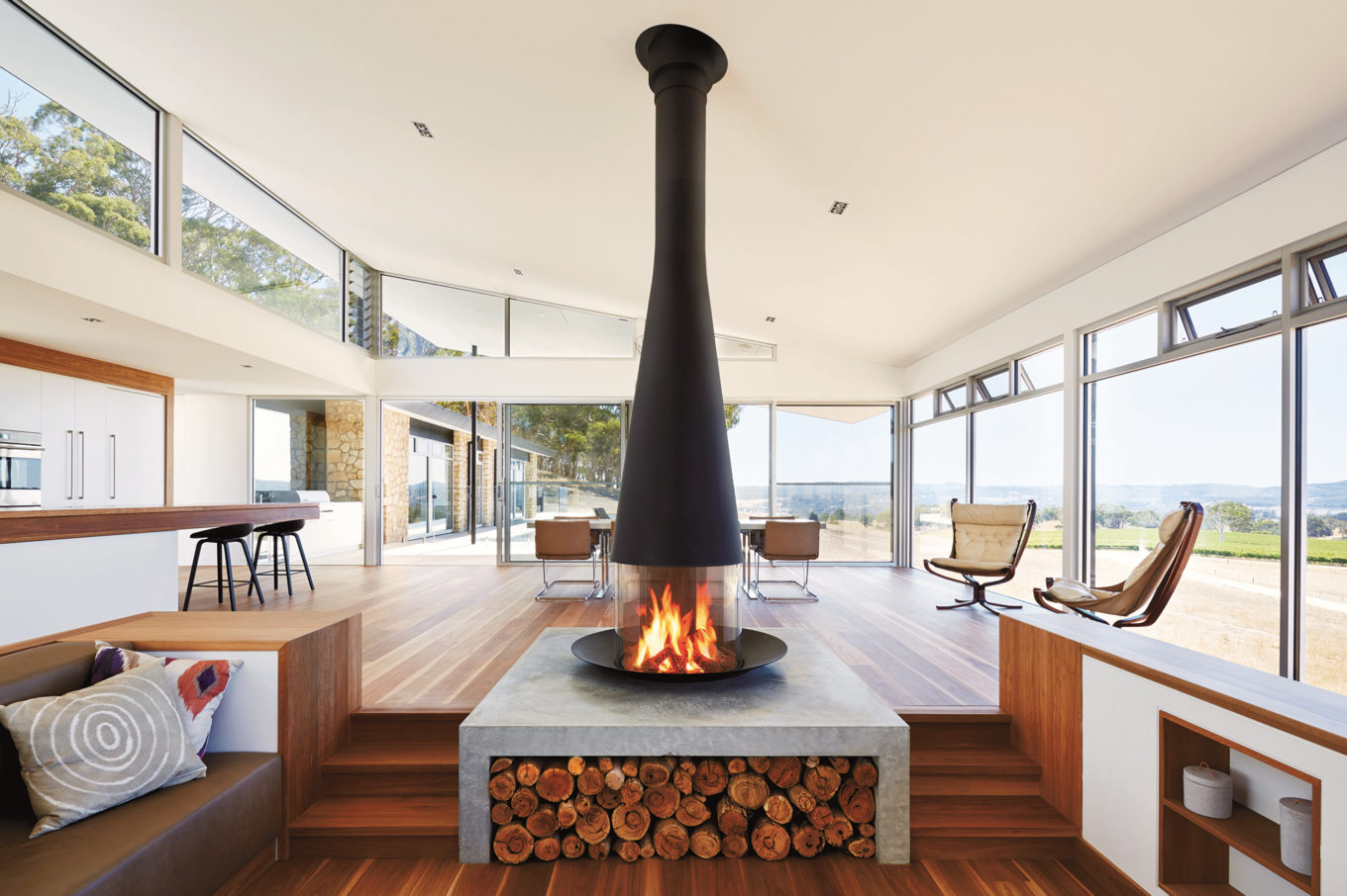 Floor mounted steel fireplace in a modern concrete and wood interior.