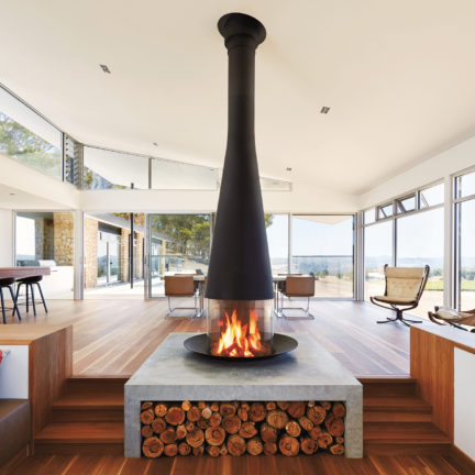 Floor mounted steel fireplace in a modern concrete and wood interior.