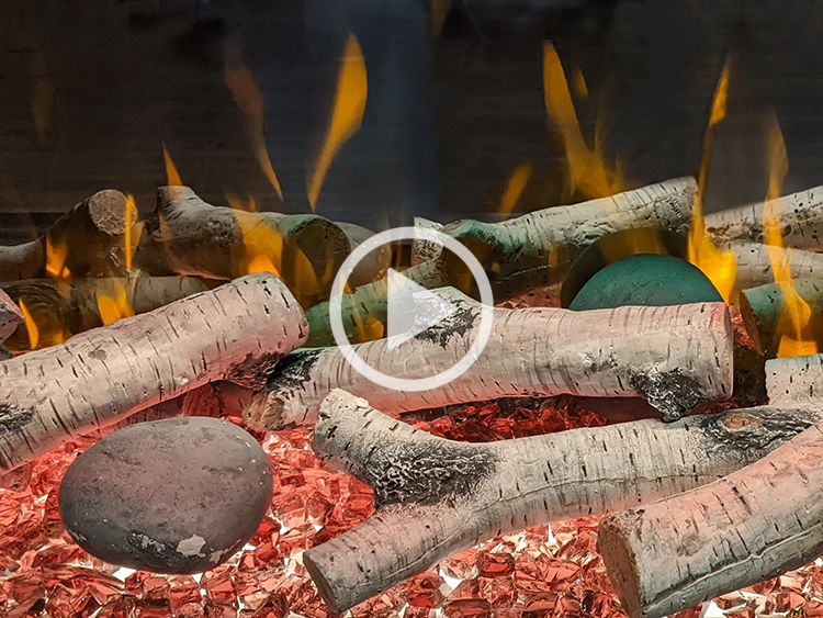 Birch logs, dark stones, and orange glass fireplace decoration.